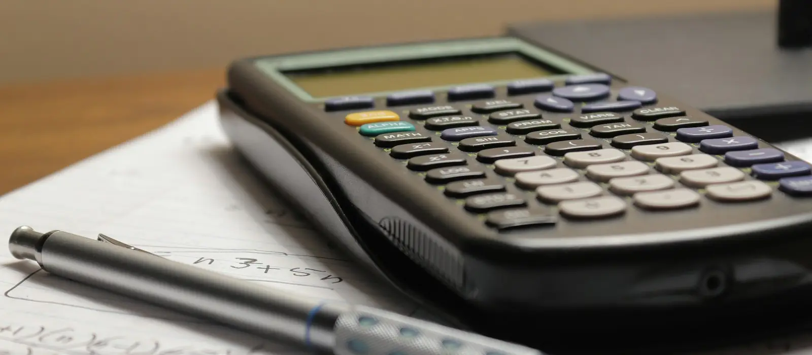 A calculator and a pen on a sheet of paper