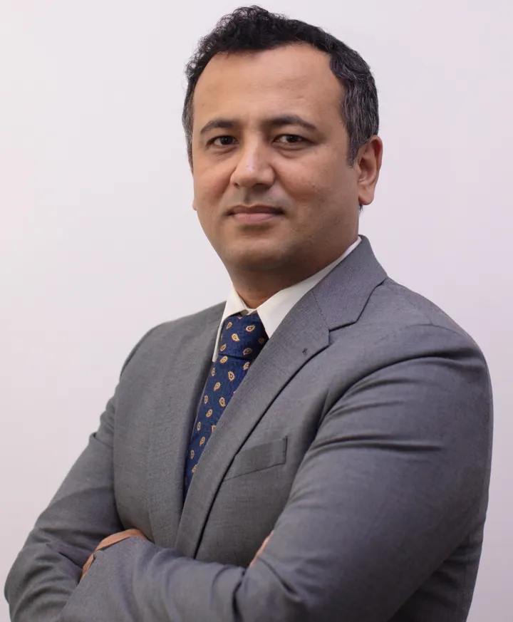 Hassan Mahboob in a grey suit, arms folded